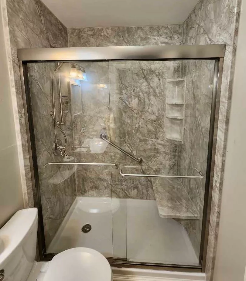 Completed walk-in shower with brushed nickel fixtures and sliding shower door.