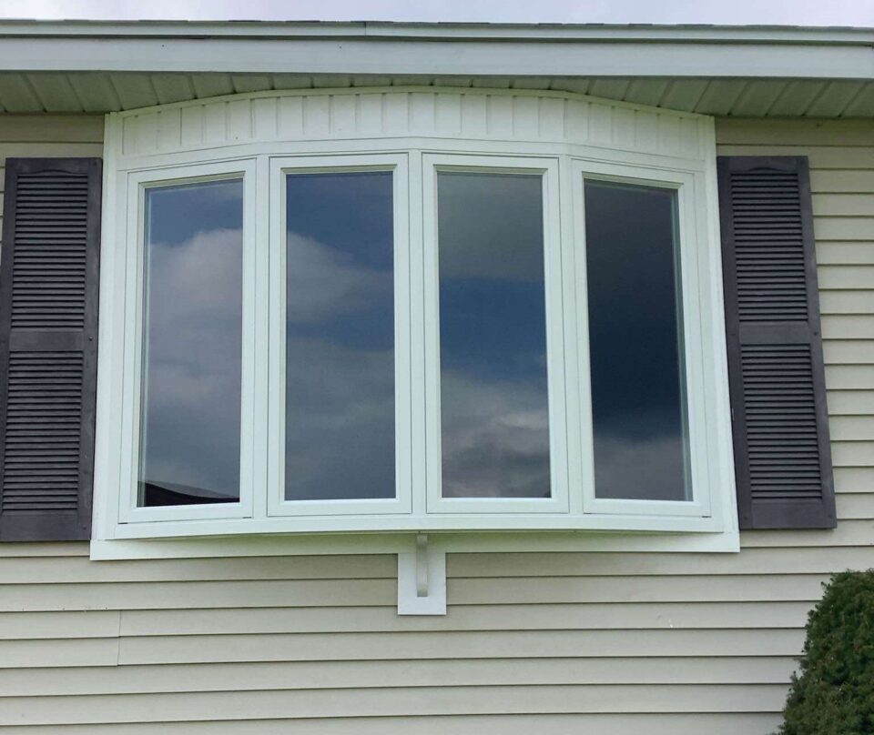 New four-lite bow window in white with black shutters.