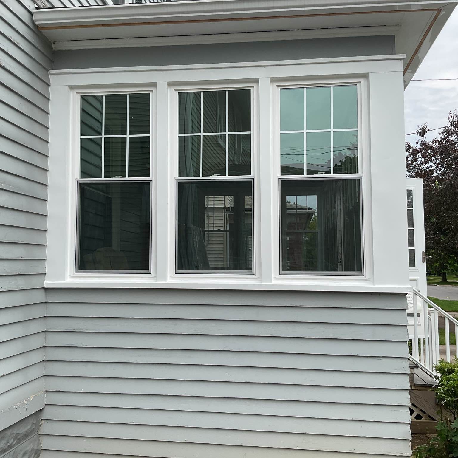 A row of perfectly aligned white vinyl windows, installed as part of a complete home window replacement project by New York Sash in Utica, NY, enhancing both the appearance and value of the home.