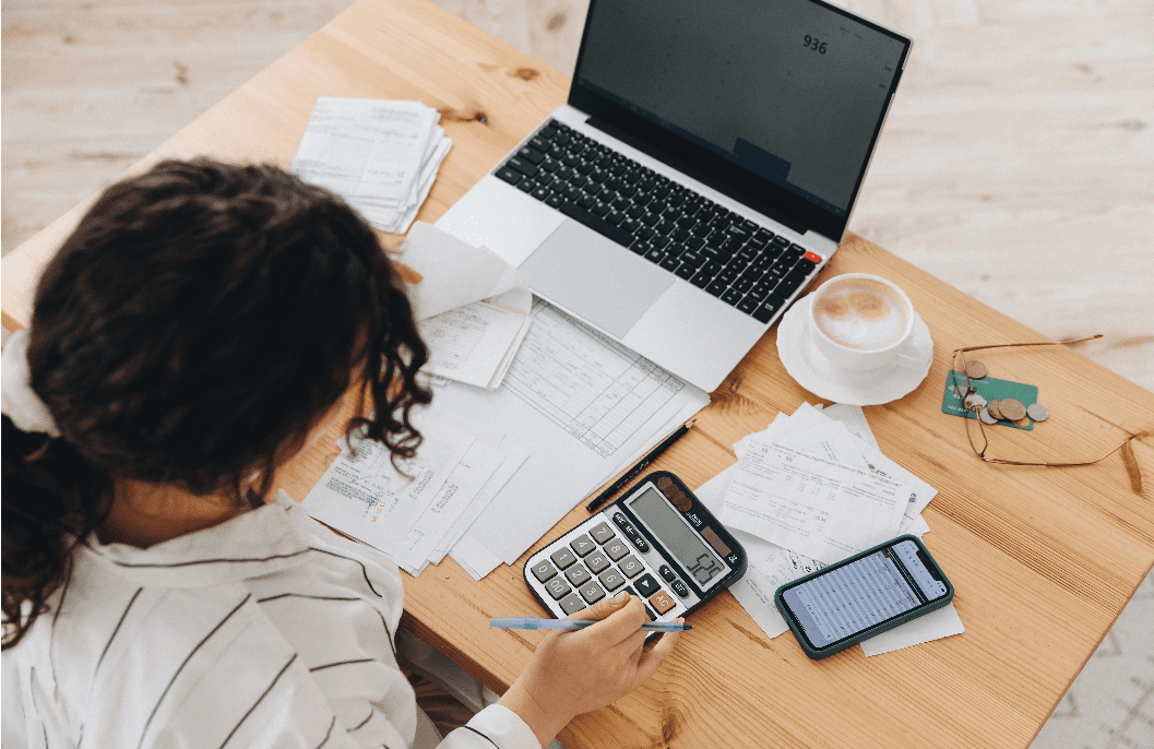 Women budgeting women at computer with calculator budgeting.